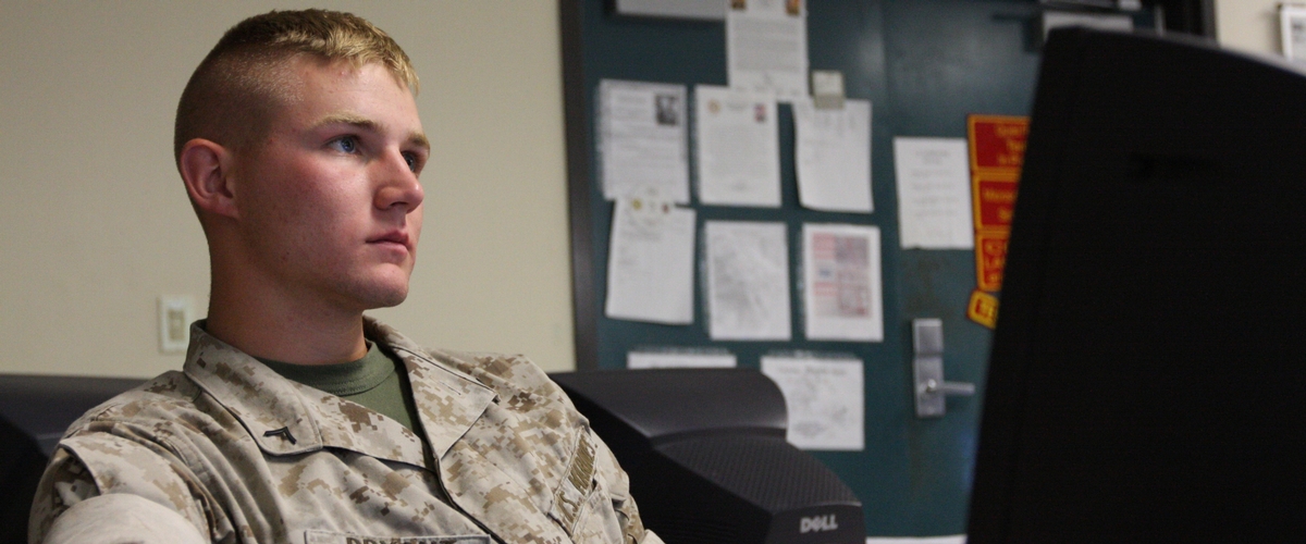 Image of USMC Marine looking at a desktop monitor.