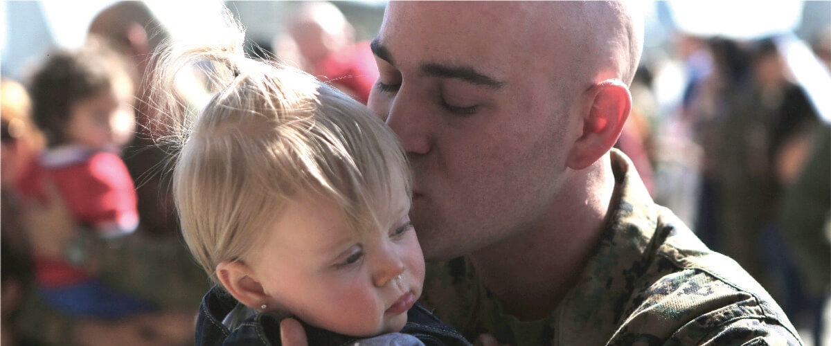 Image of Marine father kissing his baby.