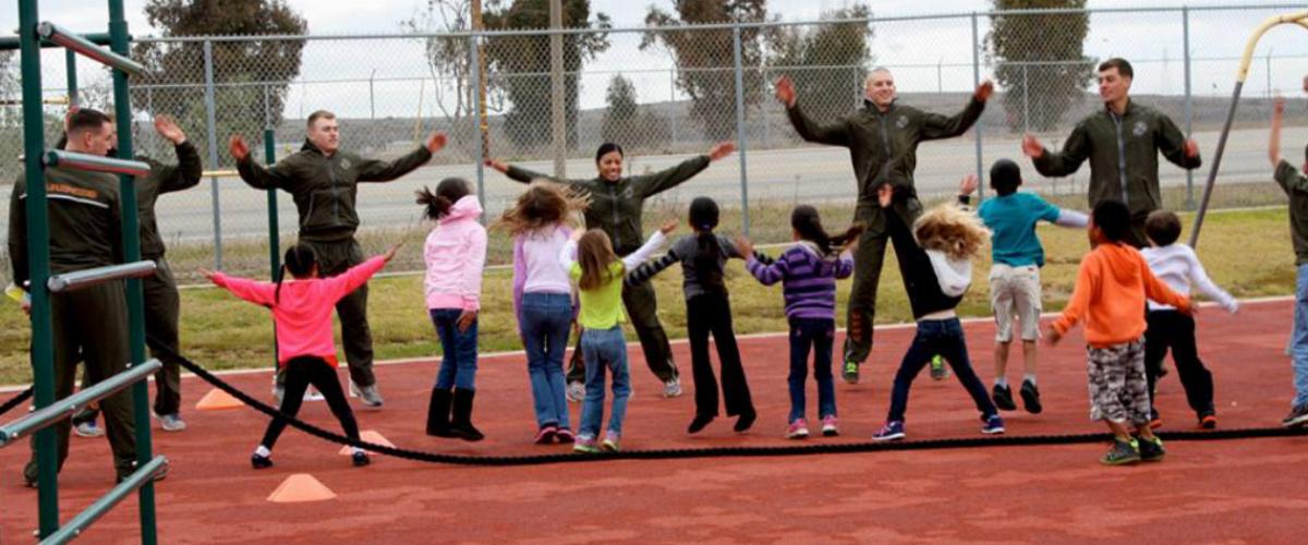 Image of Marines doing jumping jacks with children.
