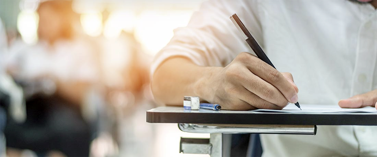 Image of a man taking a test at a school desk.