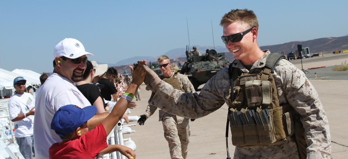 Marine high fiving a child at the Miramar Air Show.